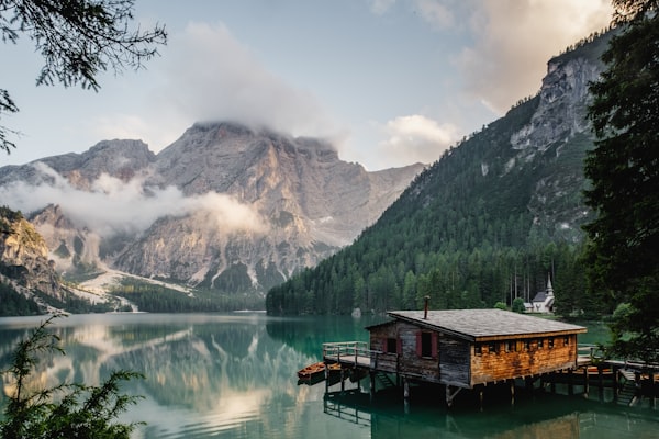 A quiet mountain lake in morning mist with a small wooden cabin